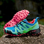 Blauer und grüner Trailrunning-Schuh mit pinker Sohle auf Felsen, ideal für Outdoor-Sport.