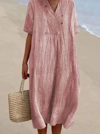 Frau in rosa Leinenkleid am Strand mit Strohtasche, Sommermode, lässiger Stil.