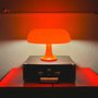 Orange Tischlampe auf schwarzem Koffer, modernes Design, warmes Licht, Inneneinrichtung.