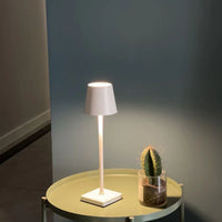 Weiße Tischlampe auf rundem Tisch neben kleinem Kaktus, modernes Design, Innenbeleuchtung.