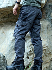 Mann in grauer Outdoor-Hose und Wanderschuhen vor Felswand, ideal für Trekking und Klettern.