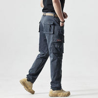 Mann in grauer taktischer Hose mit Seitentaschen, beige Stiefel, Outdoor-Bekleidung.
