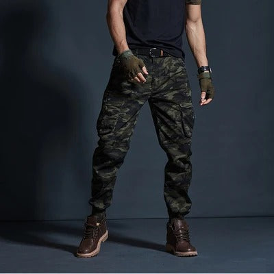 Mann in Camouflage-Cargohose, schwarze T-Shirt, braune Stiefel, taktische Handschuhe.