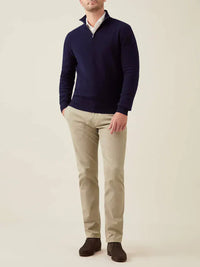 Mann trägt dunkelblauen Kaschmir-Pullover mit Reißverschluss, beige Hose, braune Schuhe.