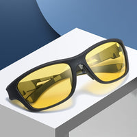 Schwarze Sonnenbrille mit gelben Gläsern auf weißem Podest, modisches Accessoire.