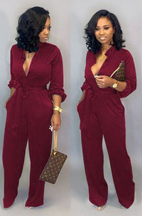 Frau in rotem Jumpsuit mit Gürtel, hält braune Designer-Handtasche, elegante Mode.