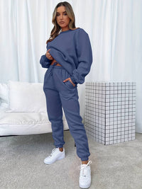 Frau in blauem Jogginganzug, weiße Sneaker, modernes Wohnzimmer, gemütliche Mode, Freizeitkleidung.