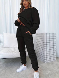 Frau in schwarzem Jogginganzug, weiße Sneaker, modernes Wohnzimmer, Freizeitmode.
