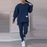 Frau in dunkelblauem Trainingsanzug, weiße Sneaker, modernes Freizeitoutfit, Innenraum.