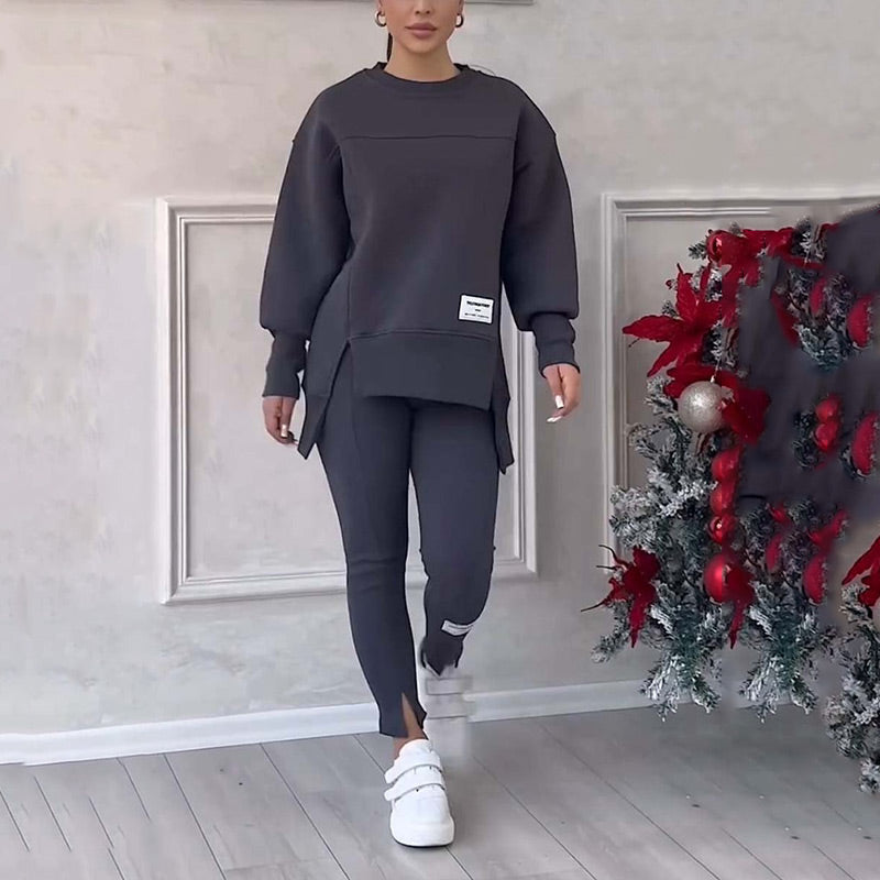 Frau in grauem Trainingsanzug, weiße Sneaker, neben Weihnachtsbaum, Innenraum.