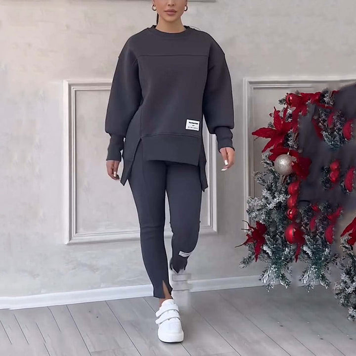 Frau in grauem Trainingsanzug, weiße Sneaker, neben Weihnachtsbaum, Innenraum.