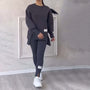Damen-Sportanzug, dunkelgrau, langärmelig, mit weißen Sneakers, lässige Freizeitmode.