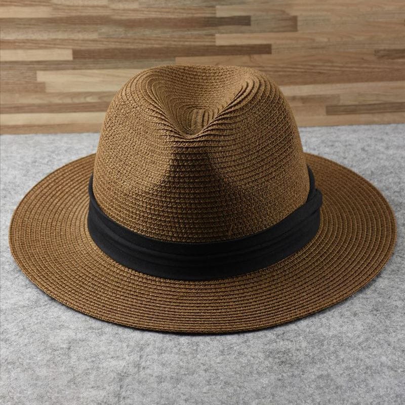 Brauner Fedora-Hut aus Stroh mit schwarzem Band auf grauem Hintergrund, stilvoll und modern.