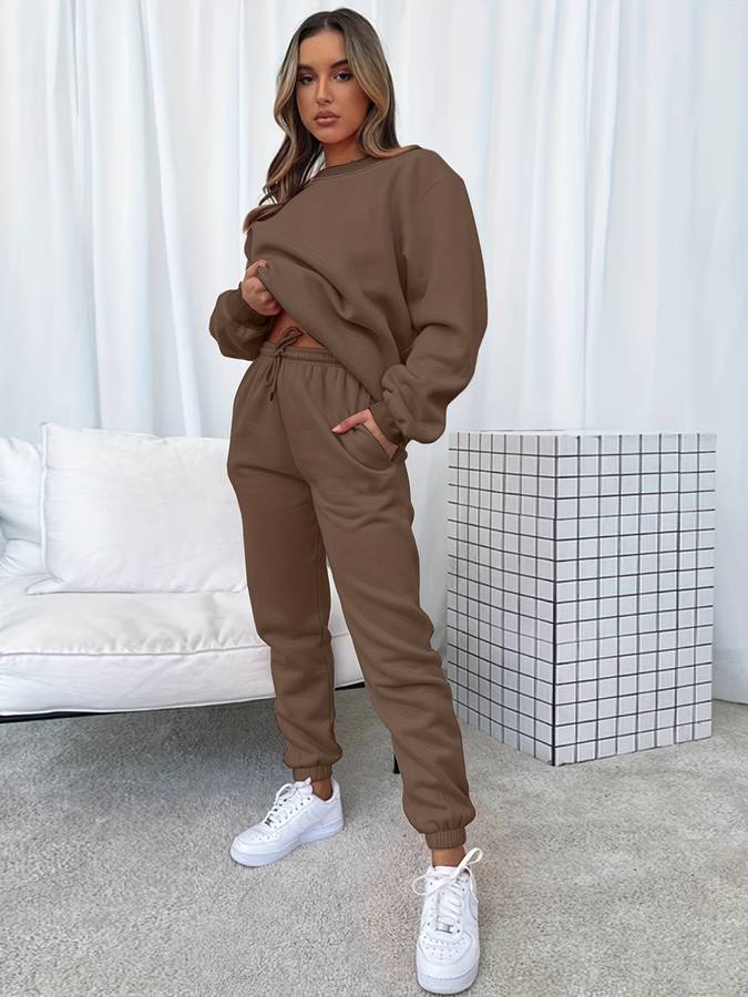 Frau in braunem Jogginganzug, weiße Sneaker, modernes Wohnzimmer, gemütliche Mode.