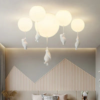 Moderne Deckenleuchte mit weißen Kugeln und hängenden Figuren, ideal für Wohnzimmerbeleuchtung.