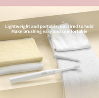 Elektrische Zahnbürste weiß, modern, mit Ersatzbürstenkopf auf Handtuch im Badezimmer.