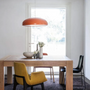 Moderner Essbereich mit Holztisch, gelbem Stuhl, roter Hängelampe und Blumenvasen.