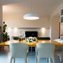Moderner Essbereich mit gelbem Tisch, weißen Stühlen und Hängelampe in stilvollem Interieur.