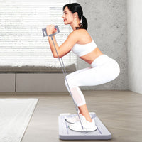 Frau trainiert mit Fitnessgerät, Widerstandsbänder, weißes Sportoutfit, Heimtraining, Wohnzimmer.