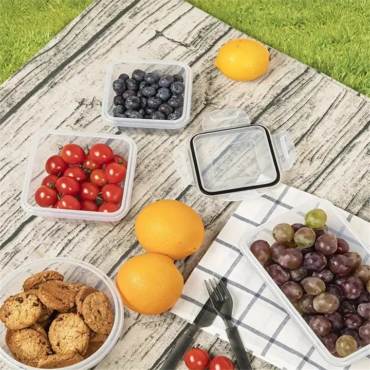 Frischhaltedosen mit Obst, Keksen und Tomaten auf Holztisch im Freien, Picknick, Sommer.