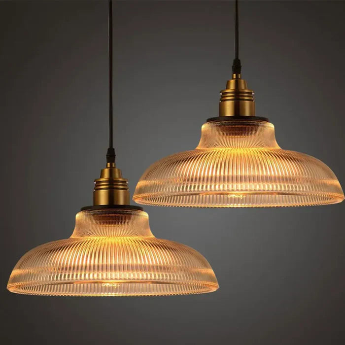 Zwei hängende Vintage-Pendelleuchten aus Glas mit warmem Licht, ideal für Wohnzimmerbeleuchtung.