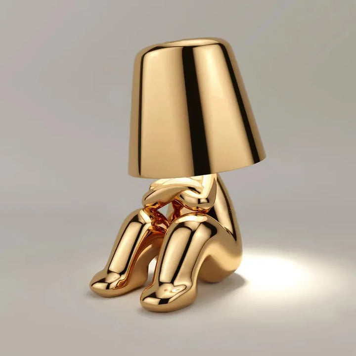Goldene Tischlampe in Form einer sitzenden Figur, modernes Design, dekorative Beleuchtung.