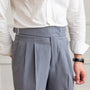Mann in weißem Hemd und grauer Anzughose mit Gürtel, Businessmode, elegante Herrenbekleidung.