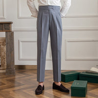Graue Herrenanzughose, elegant, aus Wolle, mit Falten, getragen mit braunen Loafern, Holzboden.