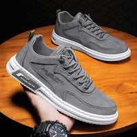 Graue Herrensneaker aus Leder mit weißer Sohle, modisches Design, auf Holztisch.