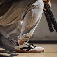 Grauer Jogginganzug mit schwarzen und weißen Sneakers, Indoor-Training, Seil in der Hand.