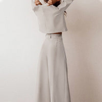 Grauer Damenanzug, weites Bein, elegantes Design, minimalistischer Stil, hochwertige Mode.