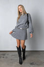 Frau in grauem Strickpullover und Rock, schwarze Stiefel, modisches Outfit, Herbstmode.
