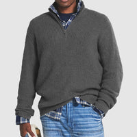 Grauer Herrenpullover mit Reißverschluss, gerippt, über kariertem Hemd, lässiger Stil.
