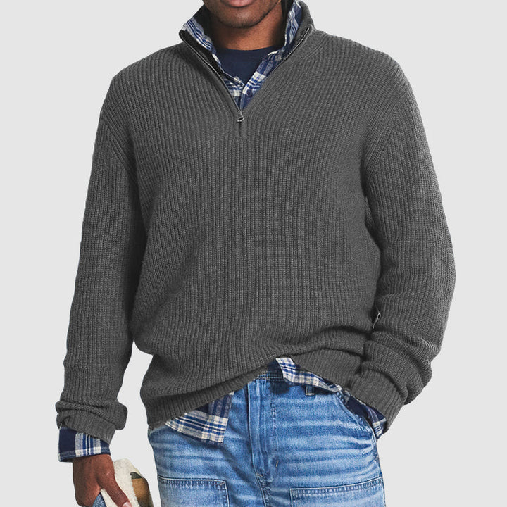 Grauer Herrenpullover mit Reißverschluss, gerippt, über kariertem Hemd, lässiger Stil.