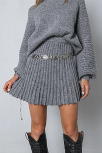 Grauer Strickpullover und Faltenrock mit silbernem Gürtel, Damenmode, Herbstoutfit.