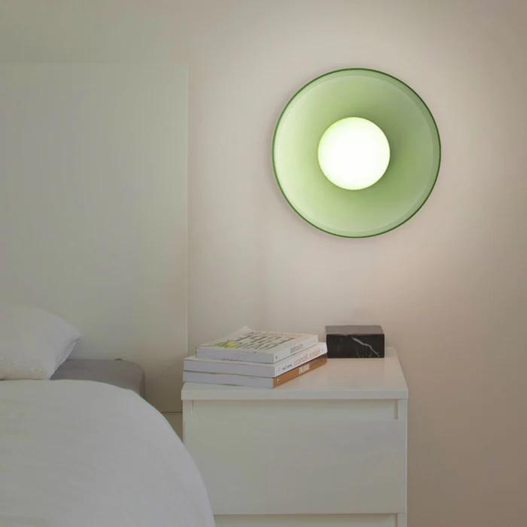 Grüne Wandleuchte im modernen Schlafzimmer, rundes Design, über weißem Nachttisch.