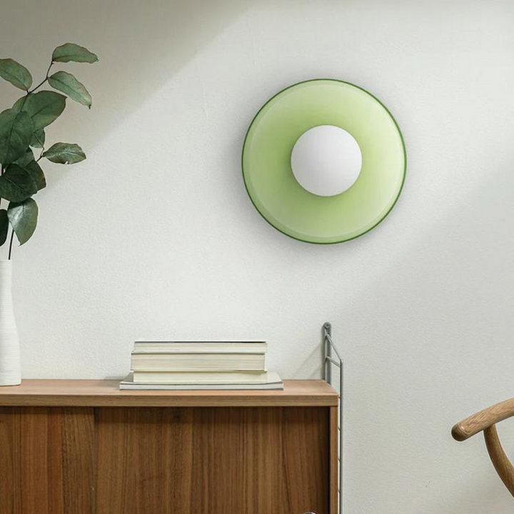 Grüne Wanduhr mit weißem Zifferblatt, modernes Design, Holzkommode, Zimmerpflanze.