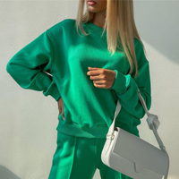 Frau in grünem Sweatshirt und Hose, trägt weiße Umhängetasche, modisch, lässig, Streetwear.