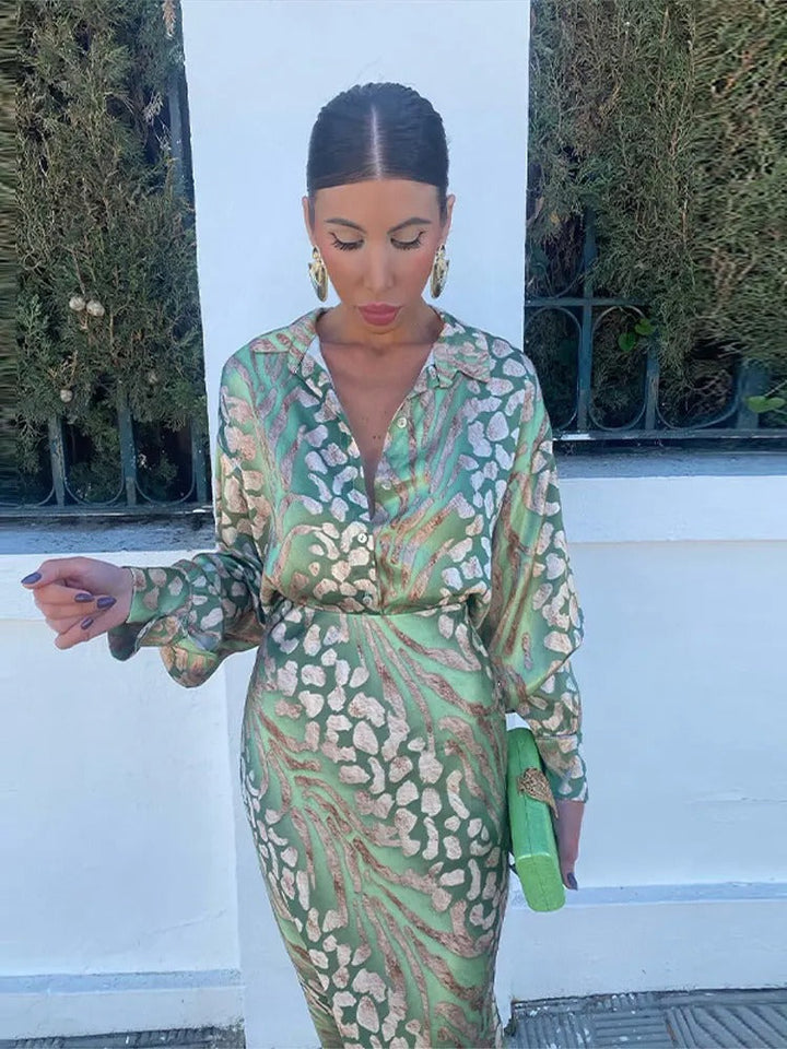 Frau in grünem Seidenkleid mit Muster, hält grüne Clutch, elegante Mode, draußen.