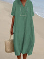 Frau im grünen Leinenkleid am Strand mit Strohtasche, Sommermode, lässiger Stil.