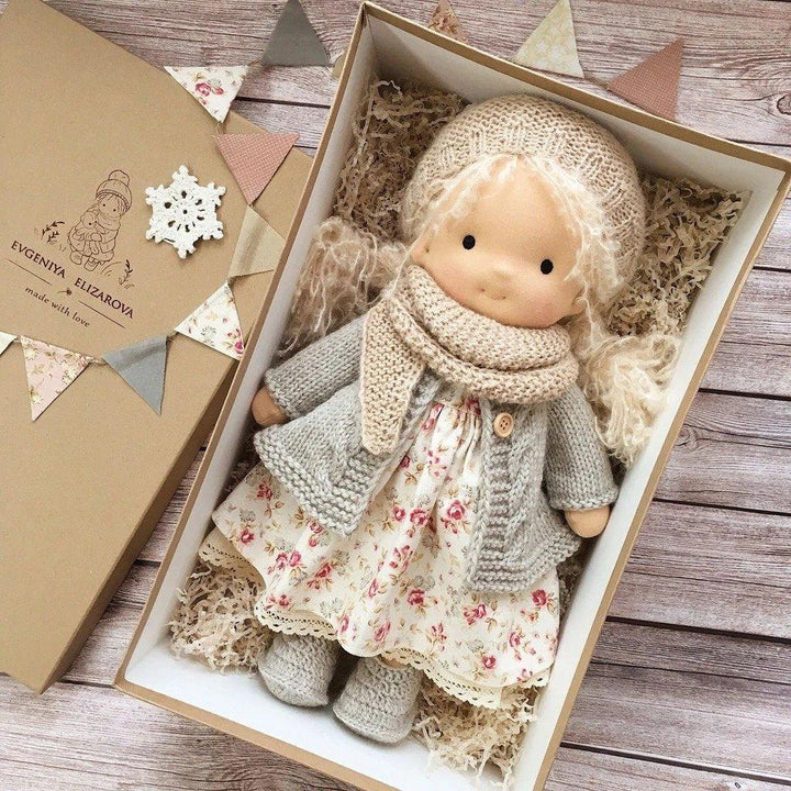 Handgemachte Waldorf-Puppe mit Strickkleidung und Blumenkleid in Geschenkbox.