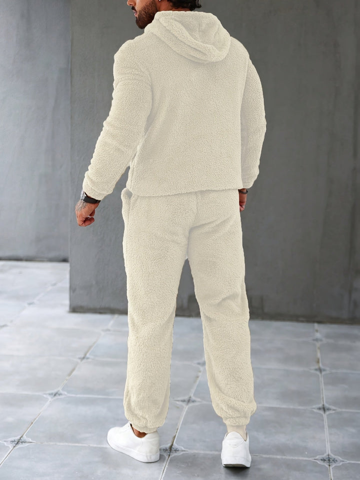 Mann in cremefarbenem Fleece-Trainingsanzug, Kapuzenjacke und Jogginghose, gemütliche Mode.