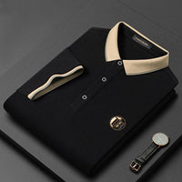 Schwarzes Polohemd mit beigem Kragen, Knöpfen und Logo, neben einer Armbanduhr.