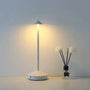 Moderne weiße LED-Tischlampe neben Duftstäbchen in Vase, minimalistisch, energiesparend.
