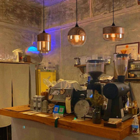 Gemütliches Café-Interieur mit Holztresen, Kaffeemaschine und hängenden Holzlampen.