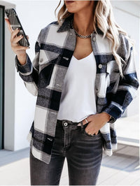 Frau in kariertem Hemd, weißem T-Shirt, Jeans, hält Smartphone, modisch, lässiger Look.