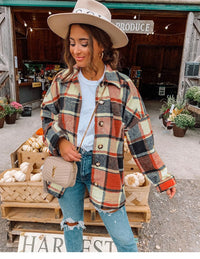 Frau in karierter Jacke und Hut vor Bauernmarkt mit Kürbissen, Jeans, Umhängetasche.