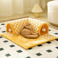 Gelber Katzentunnel und Bett aus Plüsch mit kariertem Muster, Katze liegt darauf.