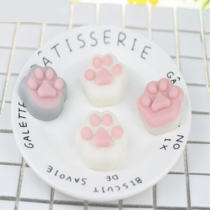 Kawaii Katzenpfote Squishy Stressball, rosa und weiß, auf Teller, Stressabbau Spielzeug.