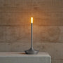 Moderne LED-Tischlampe, schlankes Design, graues Metall, warmweißes Licht, minimalistisch.